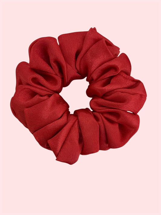 Red scrunchie on a pink background. Scarlet red luxury satin scrunchie medium 4 inches